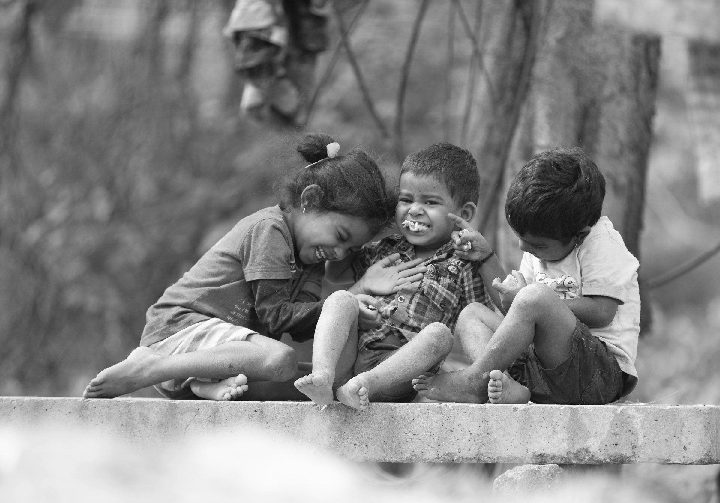 Three Venezuelan children laughing, black-and-white photograph.